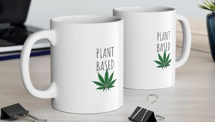 Due tazze bianche con le parole "Plant Based" e una foglia di marijuana verde stampate.